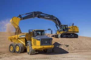 John Deere excavator emptying construction debris into articulated dump truck. Illustrates the importance of the RE568454 John Deere DPF and how it can be replaced by RoadwarriorÃ¢â‚¬â„¢s D2012-SA.