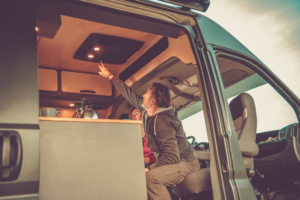 Man reaches up to turn on RV light. This image shows how changing your bulbs can improve RV energy efficiency. Another good method is upgrading to lithium RV batteries. 